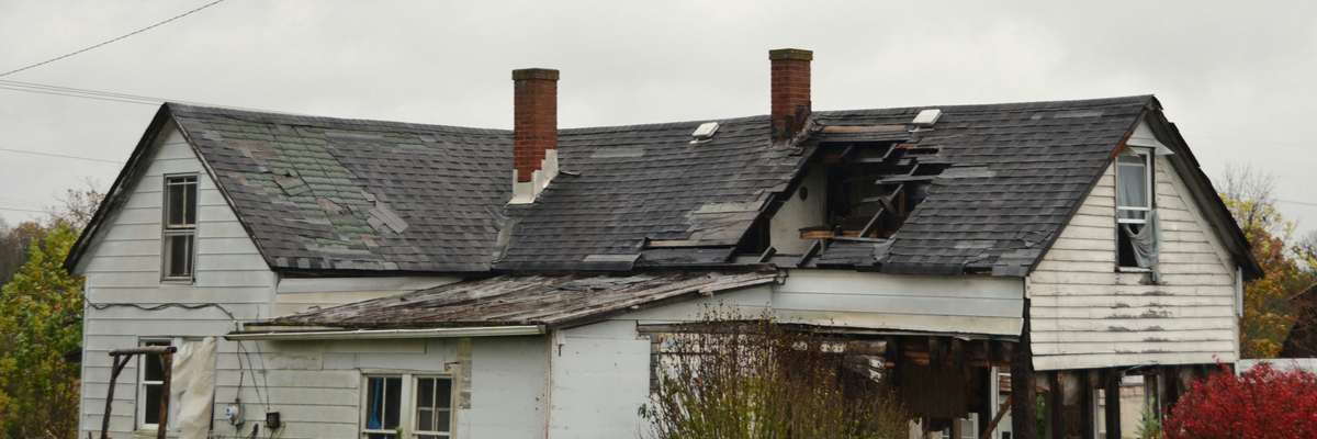Storm-damaged shingles on a residential roof with missing and lifted tabs.