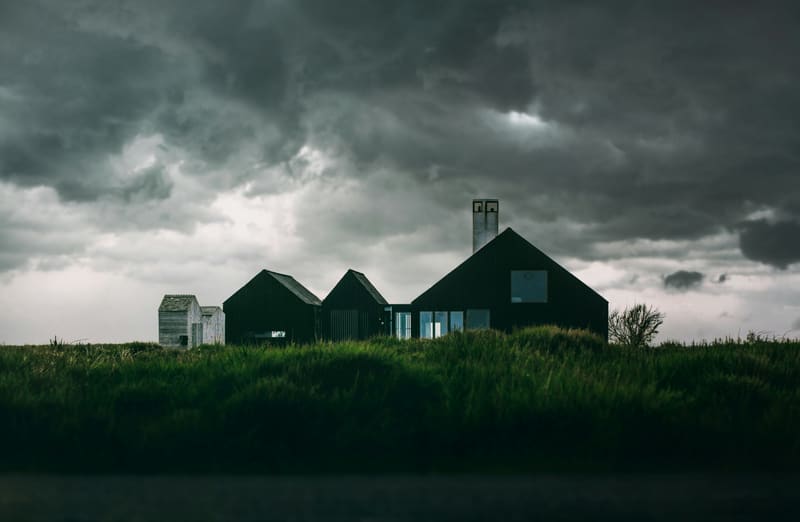 Dark houses silhouetted against a stormy sky