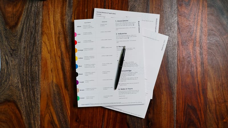 Printed forms spread on a dark wood table