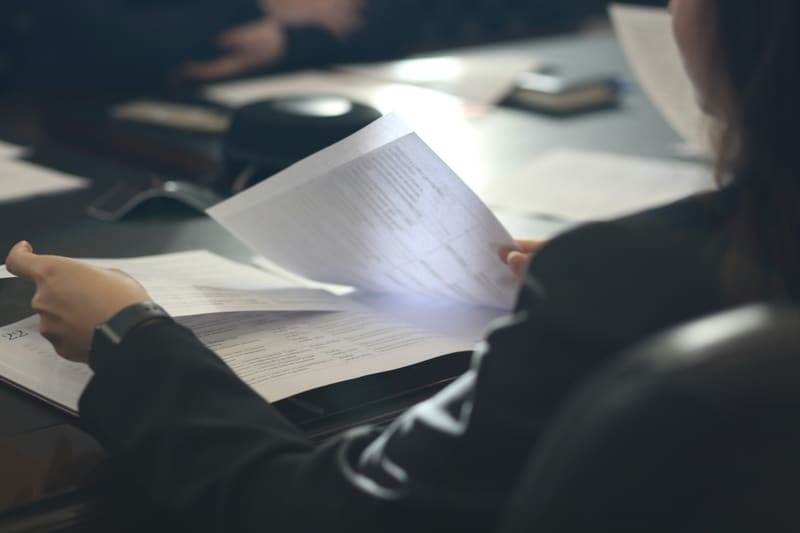 Person reviewing dense paperwork on a dark desk