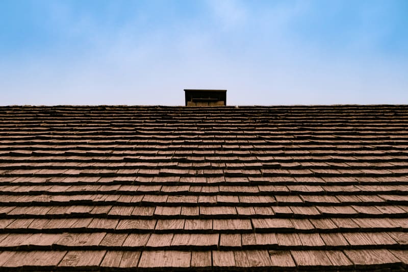 Wood shake roof with vent against blue sky