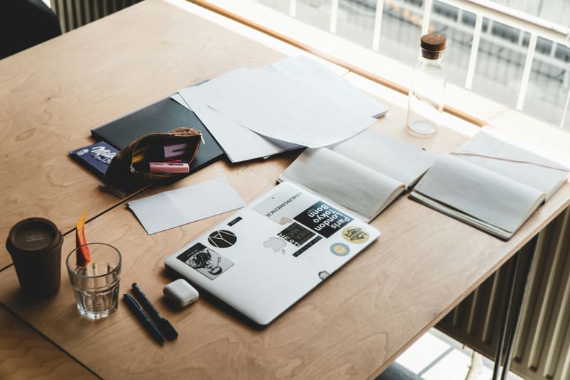 Desk workspace with laptop, papers, and notebook